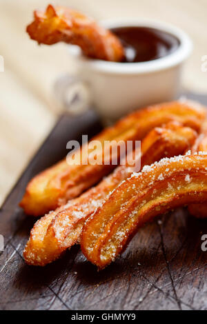 Churros con Chocolate, eine typisch spanische süßen Snack auf einem rustikalen Holztisch Stockfoto