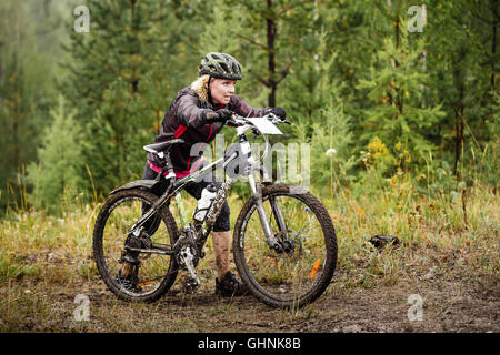 Blondes Mädchen geht in die Berg mit meinem Fahrrad bei regionalen Wettkämpfen am Crossrad Stockfoto