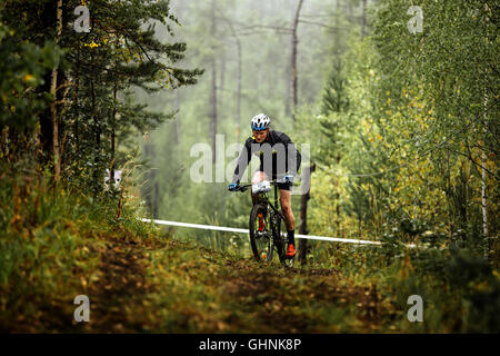 männlicher Athlet Mountainbiker reitet im Wald bei regionalen Wettkämpfen auf cross-country-bike Stockfoto