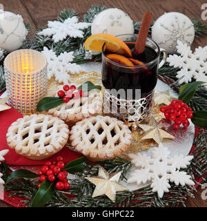 Weihnachten Glühwein gewinnen und Mince Pies, mit weißen Glitzer Schneeflocke und Gold Sterne Christbaumkugel-Dekorationen, Obst, Holly und Schnee bedeckten Stockfoto