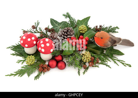 Weihnachten Deko Display mit Robin, roten Kugeln und Fliegenpilz Pilz Dekorationen mit Holly, Efeu, Schnee bedeckte Tannenzapfen Stockfoto