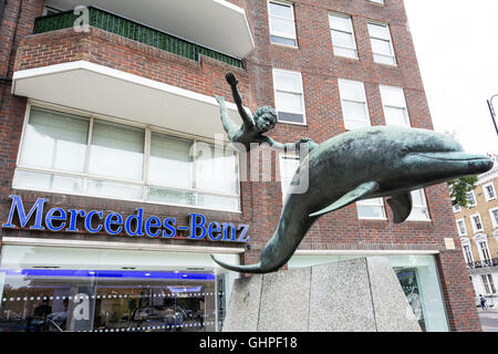 London, England, Vereinigtes Königreich: Junge mit einem Delphin durch David Wynne außerhalb der Mercedes-Benz Showroom, Chelsea, London, UK Stockfoto