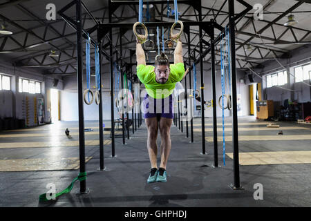 Mann tut Gym Übung an den Ringen im Fitness-Studio Stockfoto