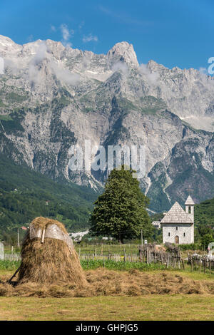 Blick über das Dorf Theth mit der Schindel überdachte Kirche und die albanischen Alpen im Hintergrund, Nordalbanien. Stockfoto