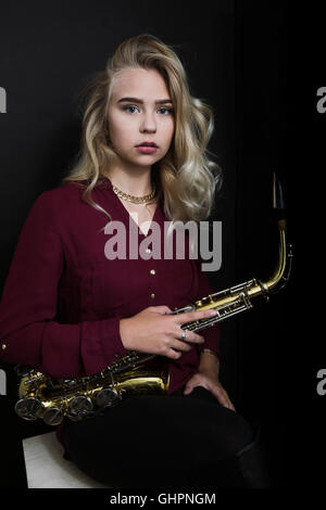 Teenager halten Saxophon auf schwarzem Hintergrund Stockfoto