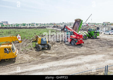 Kran, Cherry-Picker, Teleskop Stapler und Muldenkipper sind vor der Baustelle geparkt. Stockfoto