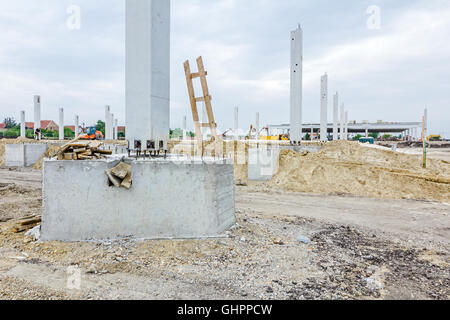 Arbeiter dienen Holzleiter auf Baustelle. Verstärkte die Stäbe sind aus dem Betonpfeiler, Basis für neue hervorstehenden Stockfoto