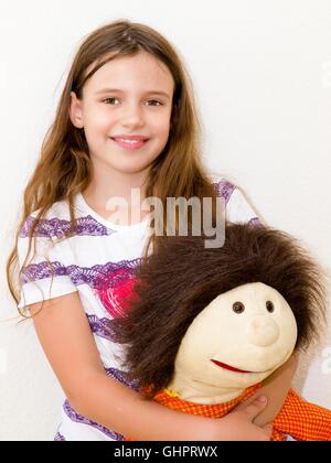 Kleines, fröhliches Mädchen mit Puppe Stockfoto