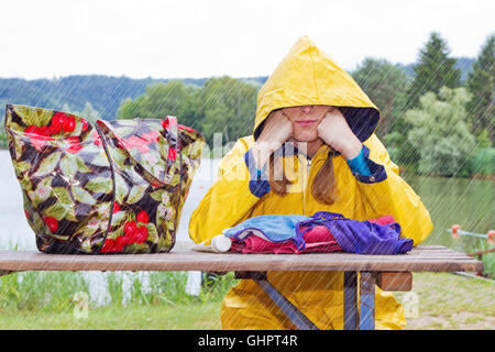 Junge Frau sitzt im Regen Stockfoto