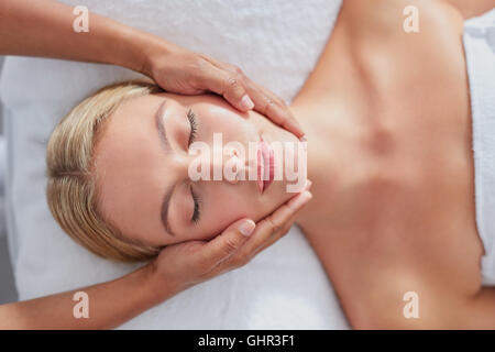 Draufsicht-Aufnahme von einer schönen jungen Frau, die immer einer Gesichtsmassage in einem spa Stockfoto