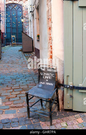 Riga, Lettland - 4. August 2016: Werbung Board auf dem alten chair'the romantische Café in der Altstadt "in der Nähe von Café und Souveni Stockfoto