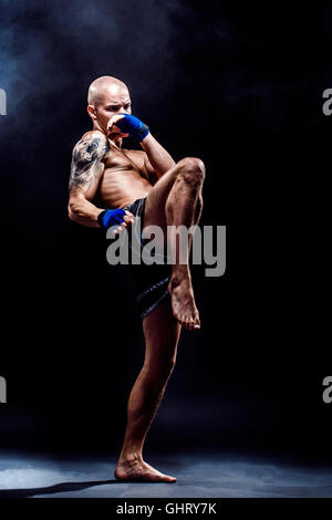 Muskuläre Kickbox oder Muay thai Kämpfer Stanzen in der Dunkelheit Stockfoto