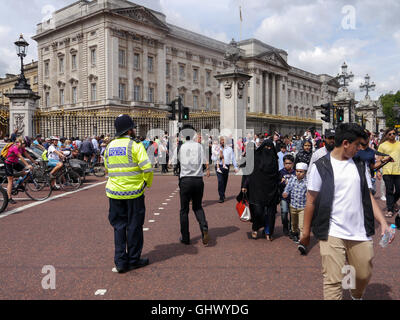 Ein Polizist beobachtet, wie Tpeople verschiedener Nationalitäten überqueren Sie die Straße außerhalb der Buckingham Palace, London, England Stockfoto