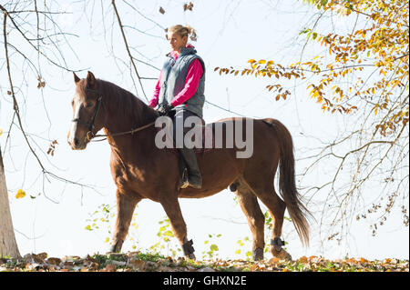 Junges Mädchen reiten durch den Wald Stockfoto