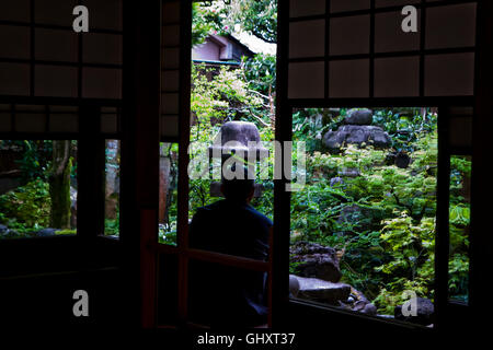 Ein Mann schaut im Hofgarten im Nomura Samurai Haus in Kanazawa, Japan. Stockfoto