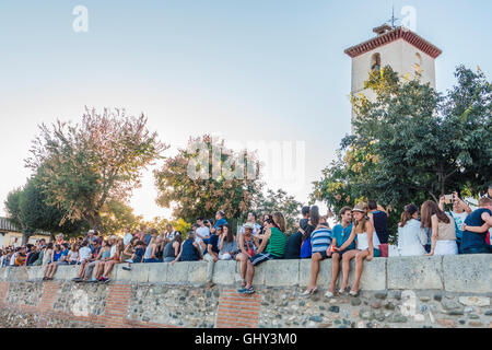 Touristen sitzen am oberen Rand der Wand an der Plaza de San Nicolás Stockfoto