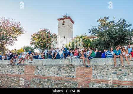 Touristen sitzen am oberen Rand der Wand an der Plaza de San Nicolás Stockfoto