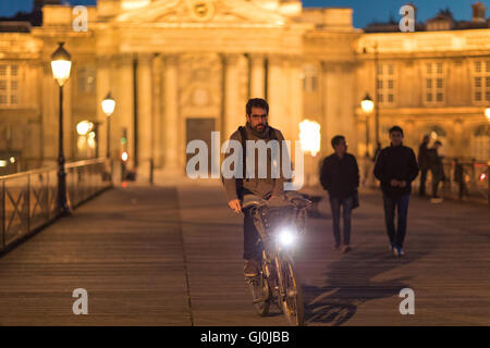 Figuren und Radfahrer auf der Pont des Arts in der Abenddämmerung, Paris, Frankreich Stockfoto