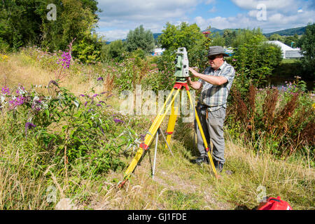 Einen professionellen Gutachter mit Leica Opti-Cal digital Theodolit Land Umfrage und Präzision Messinstrument auf einem Stativ, Mesaure die Menge an Boden und Land-Bewegung in der Nähe einer Wohnsiedlung in Abergavenny, Wales UK Monmouthsire Stockfoto