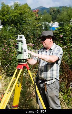 Einen professionellen Gutachter mit Leica Opti-Cal digital Theodolit Land Umfrage und Präzision Messinstrument auf einem Stativ, Mesaure die Menge an Boden und Land-Bewegung in der Nähe einer Wohnsiedlung in Abergavenny, Wales UK Monmouthsire Stockfoto