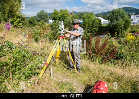 Einen professionellen Gutachter mit Leica Opti-Cal digital Theodolit Land Umfrage und Präzision Messinstrument auf einem Stativ, Mesaure die Menge an Boden und Land-Bewegung in der Nähe einer Wohnsiedlung in Abergavenny, Wales UK Monmouthsire Stockfoto