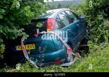 ein Auto bleibt begraben in eine Hecke nach dem gescheiterten Versuch der scharfen Kurve auf einem Land Straße England Großbritannien zu verhandeln Stockfoto