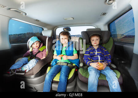 Drei glückliche Jungs sitzen im Auto Kindersitze Stockfoto