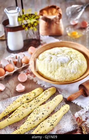 Brot-Sticks und Hefeteig fertig zum Backen, rustikale Einrichtung auf einem Holztisch. Stockfoto