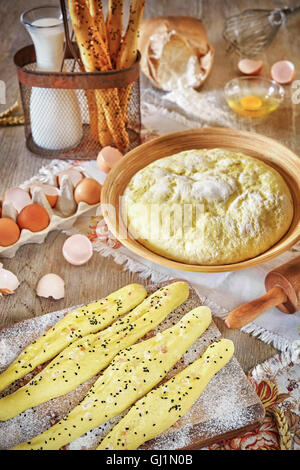 Brot-Sticks und Hefeteig fertig zum Backen, rustikale Einrichtung auf einem Holztisch. Stockfoto