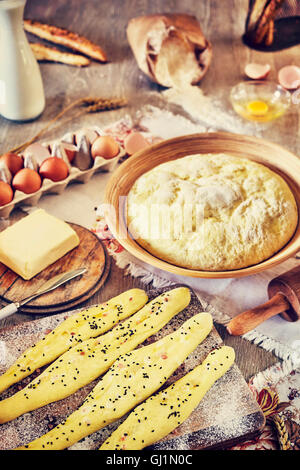 Vintage getönten Brot-Sticks und Hefeteig fertig zum Backen, rustikale Einrichtung auf einem Holztisch. Stockfoto