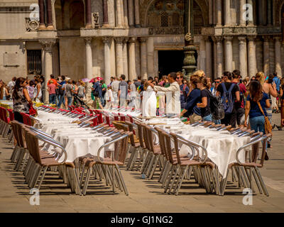Leere Tische und Stühle, zusammen mit Massen von Touristen in Markusplatz entfernt, Venedig, Italien. Stockfoto