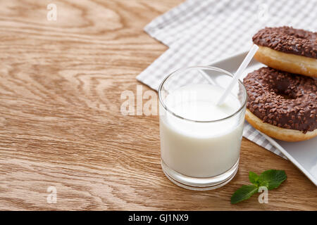 Glas Milch und Schokolade Donuts auf Holztisch Stockfoto