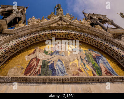 Kunstvolle Steinschnitzerei und Mosaikarbeiten einer der fünf Lünetten an der Außenseite der Markusbasilika in Venedig, Italien. Stockfoto