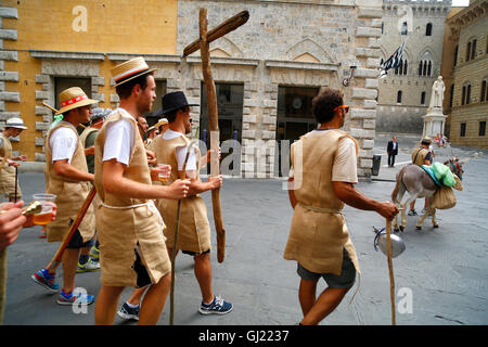 Mitglieder des Siegerteams La Lupa von Julys Il Palio-Pferderennen, Wandern mit einem Esel entlang Via Banchi di Sopra in Siena, Ital Stockfoto