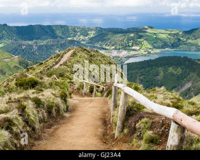 Pfad zum Aussichtspunkt. Ein Feldweg mit einem hölzernen Geländer schlängelt sich über die Hügel zu einem spektakulären Aussichtspunkt hoch über Sete Cidades. Stockfoto