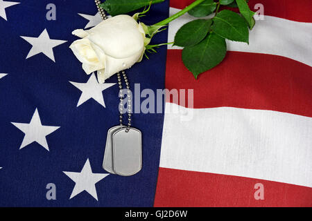 Militärische Hundemarke auf amerikanische Flagge mit weißer Rose. Stockfoto