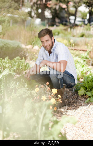 Porträt von reifer Mann kauert im Garten Stockfoto