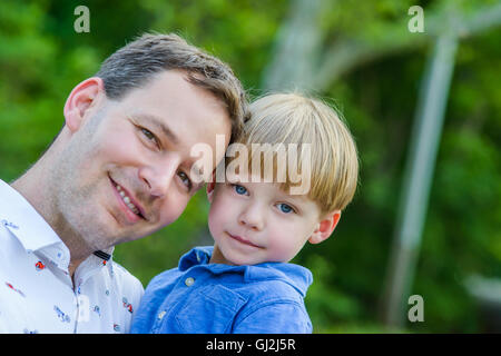 Vater Holding Sohn Blick auf die Kamera zu Lächeln Stockfoto