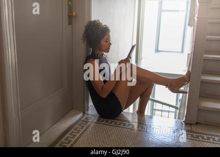 Junge Frau sitzt am oberen Ende der Treppe, mit digital-Tablette Stockfoto