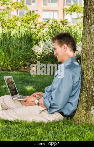 Geschäftsmann, sitzen im Freien, an Baum gelehnt, mit laptop Stockfoto