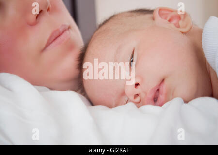 Babyjungen schlafen auf Mütter Brust Stockfoto