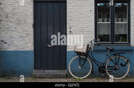 Ein einzelnes Fahrrad lehnt sich an eine Wand in den Straßen von Brügge, Belgien. Stockfoto