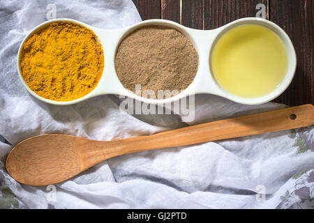 Kurkuma, Pfeffer und Olivenöl in weiße Keramikschale auf hölzernen Hintergrund. Zutaten für golden einfügen Stockfoto