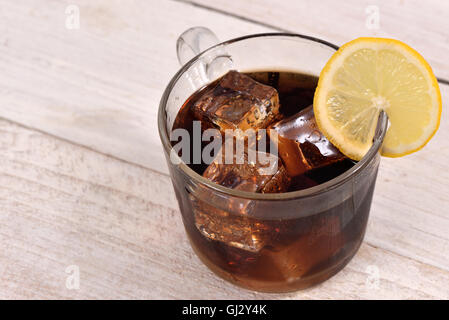 Cola-Getränk mit Ice Cube und Zitrone Scheibe auf weißem rustikalen Holz Hintergrund Stockfoto