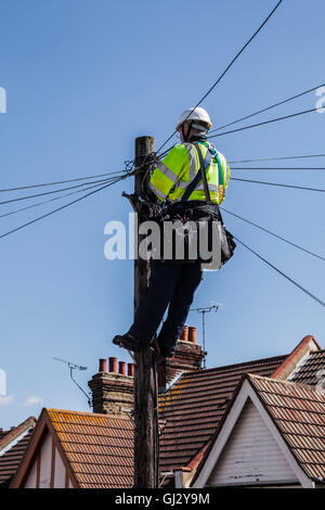 BT-Ingenieur über Telefonleitungen an der Spitze eines Mastes Stockfoto