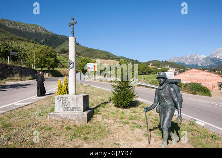 Priester in Hintergrund und Kreuz mit Statue von Walker Wandern Camino Santiago.Famous Wallfahrt Trail in der Nähe von Potes symbolisiert. Stockfoto