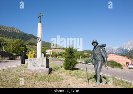 Priester in Hintergrund und Kreuz mit Statue von Walker Wandern Camino Santiago.Famous Wallfahrt Trail in der Nähe von Potes symbolisiert. Stockfoto