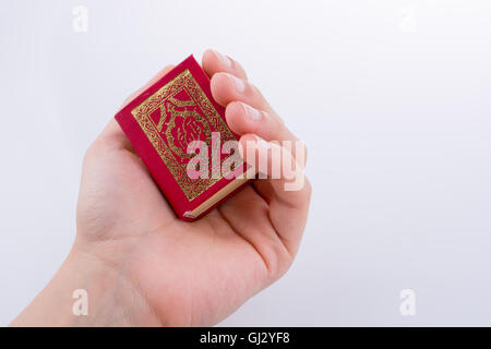 Hand, die der Heilige Koran auf weißem Hintergrund Stockfoto