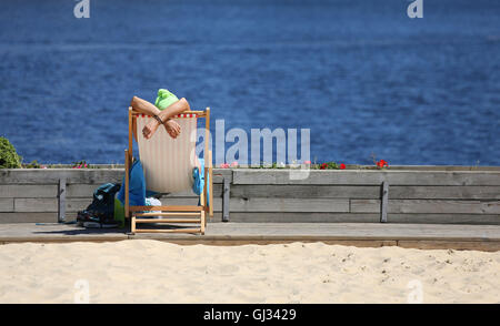 Eine Frau sonnt sich am Strand Urban London in den Royal Docks in London. Stockfoto