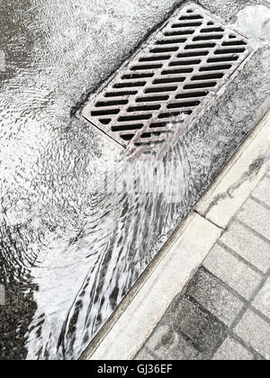 Regen Wasser fließt nach unten durch Kanalisation Rost auf Straße Stockfoto